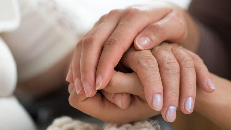 Close-up of two hands gently holding each other.