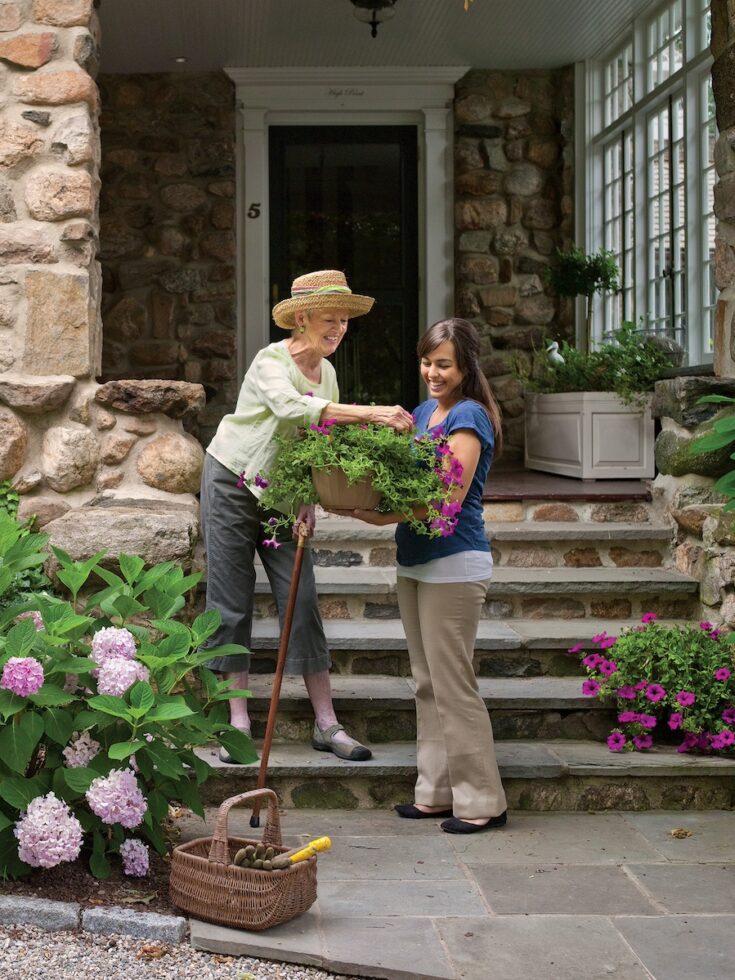 Caregiver assisting senior with gardening hydrangeas at home in Chappaqua