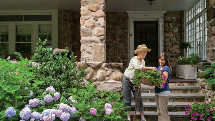 Caregiver assisting senior with gardening hydrangeas at home in Chappaqua