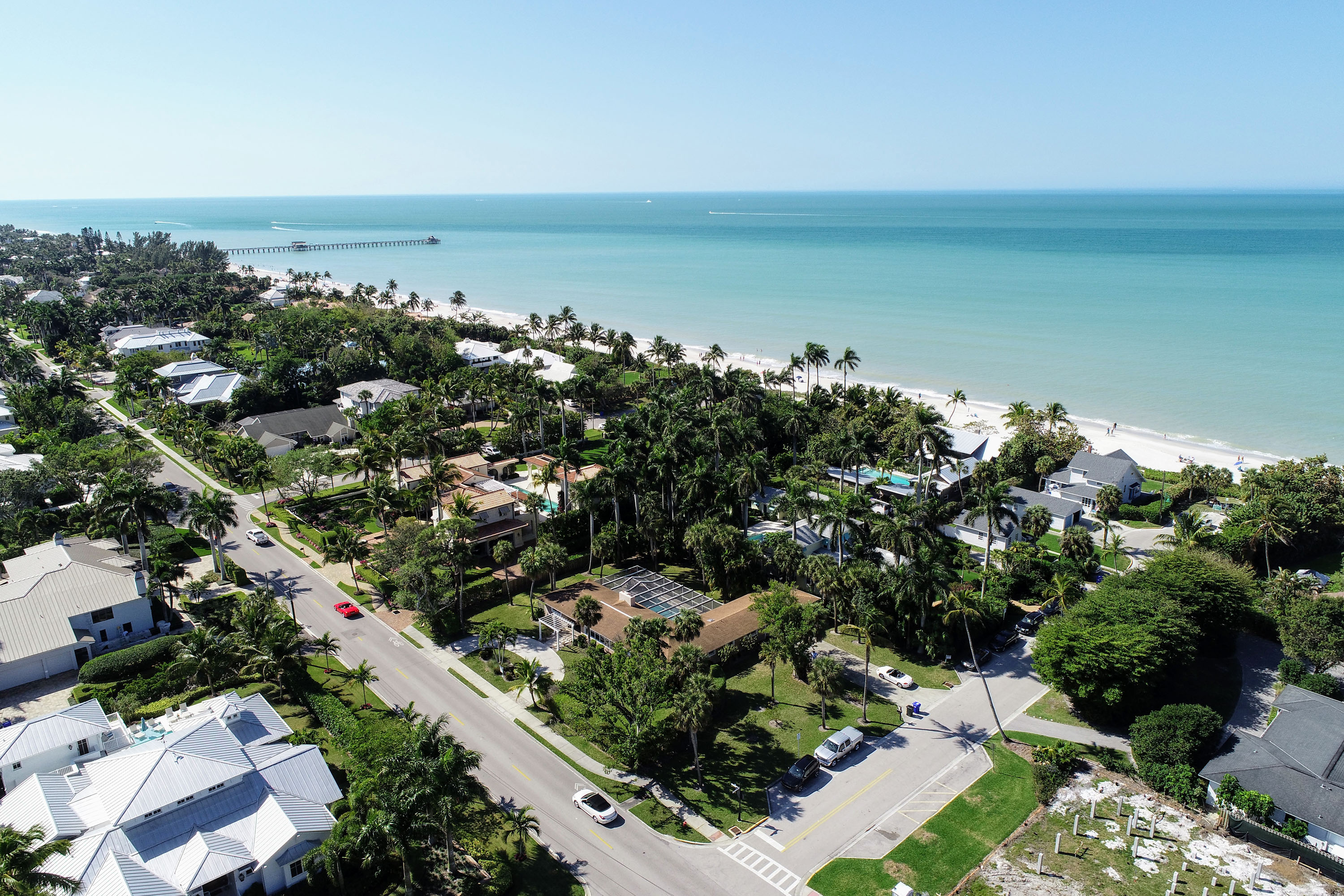 Aerial view of beachfront homes and palm-lined streets in Venice, FL.
