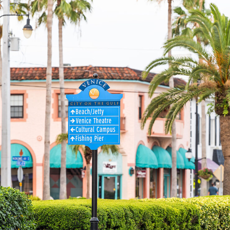 Directional sign in downtown Venice, Florida pointing to beach, theatre, cultural campus, and fishing pier.