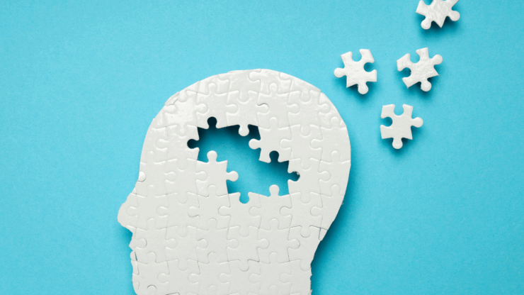 Silhouette of a head made from puzzle pieces on a blue background, with missing pieces floating away, symbolizing memory loss.