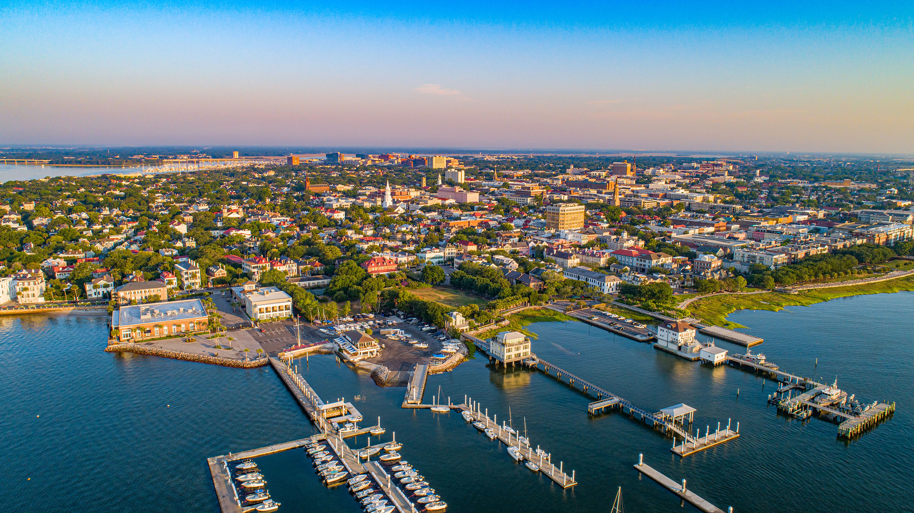 Aerial view of Charleston, South Carolina, showing a marina, buildings, and clear skies.